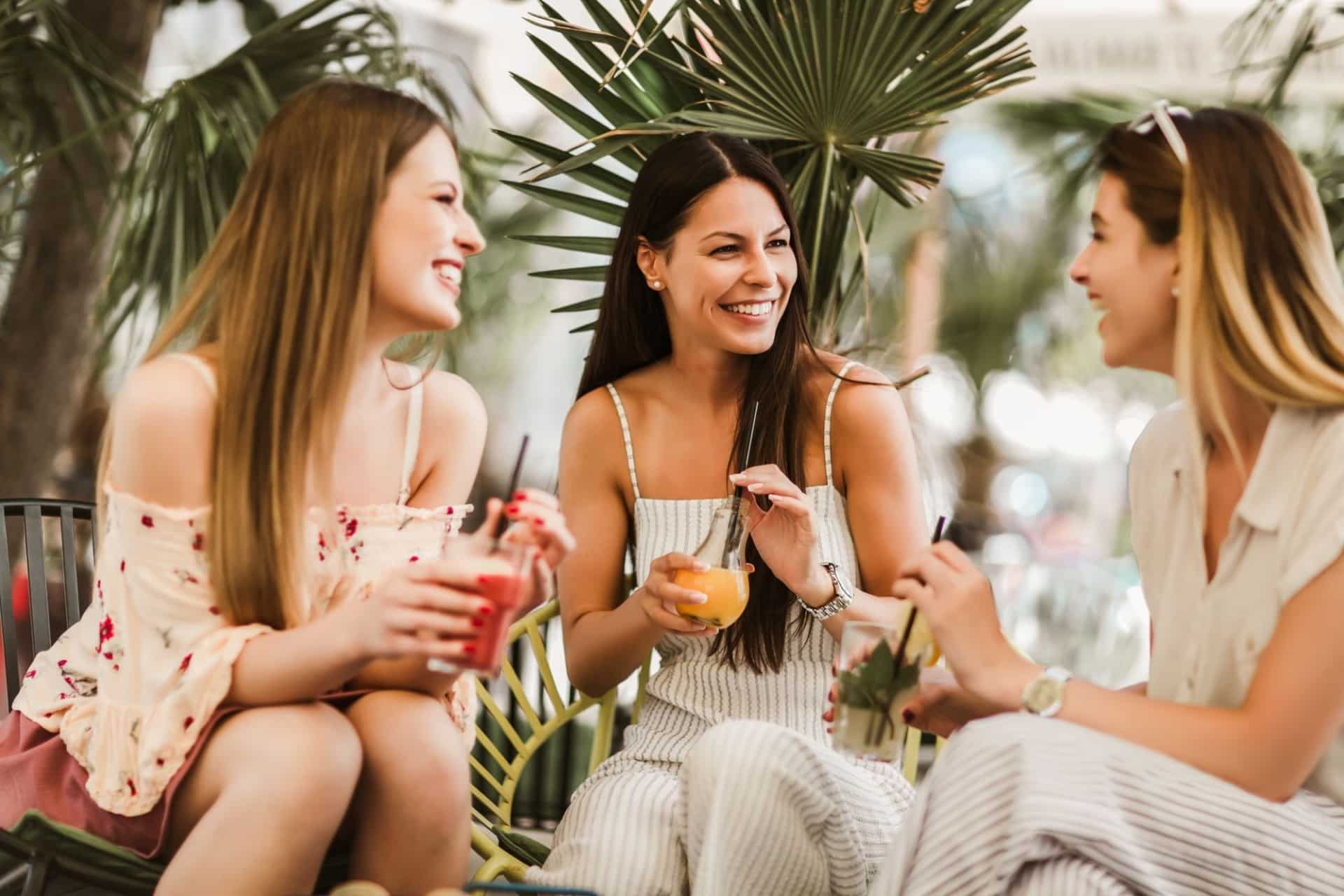 Three women with drinks in hand sitting and chatting near Fort Myers apartment The Alery istock 1271471436